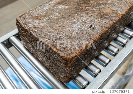 The close up image of the jagged brown natural raw rubber bales surface, lumpy solid block standard Thai rubber, in a factory. The close up image of the jagged brown natural raw rubber bales surface, lumpy solid block standard Thai rubber, in a factory. 137076371