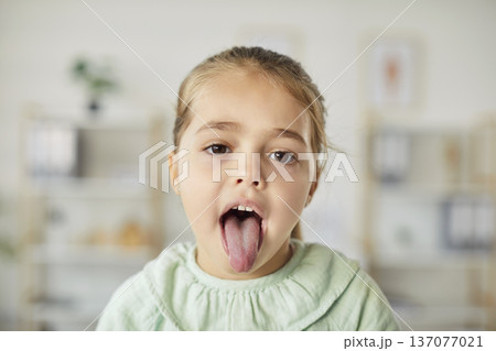Portrait Of Girl Patient Showing Tongue During Doctor's Checkup In Hospital Portrait Of Girl Patient Showing Tongue During Doctor's Checkup In Hospital 137077021