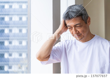 窓辺で頭を抱えるシニア男性 137077837