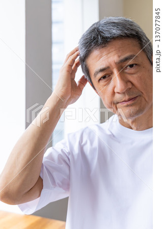 窓辺で頭を抱えるシニア男性 137077845