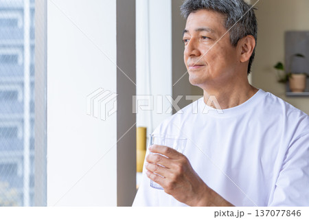窓辺で水を飲むシニア男性 137077846