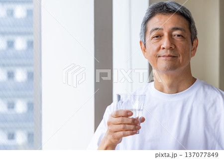 窓辺で水を飲むシニア男性 137077849