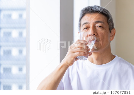 窓辺で水を飲むシニア男性 137077851