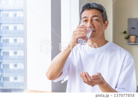 窓辺で薬を飲むシニア男性 137077858