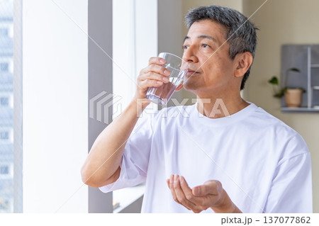 窓辺で薬を飲むシニア男性 137077862