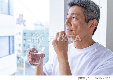 窓辺で薬を飲むシニア男性 137077867