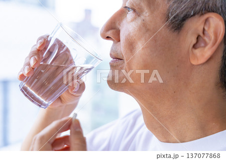 窓辺で薬を飲むシニア男性 137077868
