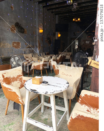 Vintage-style cafe interior with worn wooden tables and chairs, exposed brick walls, and decorative lighting creating a rustic atmosphere 137079818