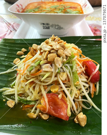Pad Thai salad with fresh vegetables, peanuts, and herbs served on a banana leaf with a bowl of soup in the background on a dining table Pad Thai salad with fresh vegetables, peanuts, and herbs served on a banana leaf with a bowl of soup in the background on a dining table 137079871