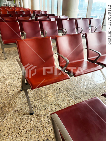 Red leather seating arrangement in a modern airport waiting area with polished granite flooring and large windows allowing natural light Red leather seating arrangement in a modern airport waiting area with polished granite flooring and large windows allowing natural light 137080112