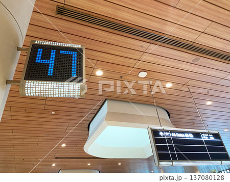 Digital display showing number 47 in blue LED lights inside a modern airport terminal with wooden ceiling and overhead information board Digital display showing number 47 in blue LED lights inside a modern airport terminal with wooden ceiling and overhead information board 137080128