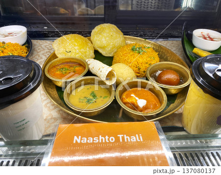 Indian food platter featuring Naashto Thali with various dishes including rice, bread, curries, and desserts displayed in a cafe setting Indian food platter featuring Naashto Thali with various dishes including rice, bread, curries, and desserts displayed in a cafe setting 137080137