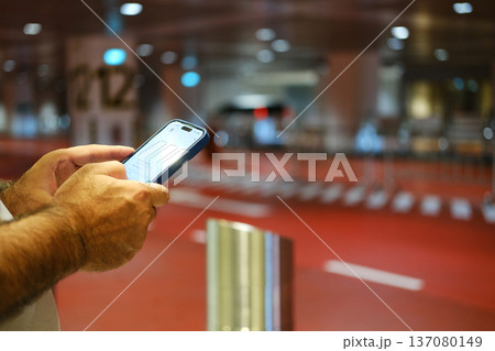 Person using smartphone to call a taxi at an airport terminal with red flooring and blurred background showing vehicle pick-up area Person using smartphone to call a taxi at an airport terminal with red flooring and blurred background showing vehicle pick-up area 137080149