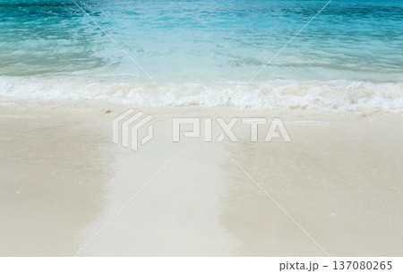 Serene beach scene in Thailand with gentle waves lapping against soft white sand under clear blue skies, showcasing the tranquil beauty of nature 137080265