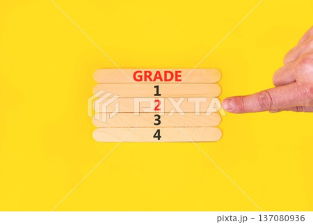 Time to grade 2 symbol. Concept word Grade 1 2 3 4 on beautiful wooden sticks. Businessman's hand. Beautiful yellow background. Business planning and time to grade 2 concept. Copy space. 137080936