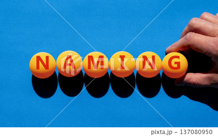 Naming or name symbol. Concept word Naming on beautiful orange table tennis ping pong balls. Beautiful blue background. Businessman's hand. Business naming or name concept. Copy space. Naming or name symbol. Concept word Naming on beautiful orange table tennis ping pong balls. Beautiful blue background. Businessman's hand. Business naming or name concept. Copy space. 137080950