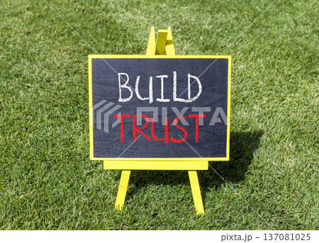 Build trust symbol. Concept words Build trust on beautiful black blackboard. Beautiful green grass lawn background. Business and build trust concept, copy space. 137081025