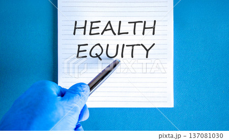 Health equity symbol. Concept words Health equity on beautiful white note. Doctor's hand in blue medical glove. Black pen. Beautiful blue background. Medical healthy lifestyle health equity concept Health equity symbol. Concept words Health equity on beautiful white note. Doctor's hand in blue medical glove. Black pen. Beautiful blue background. Medical healthy lifestyle health equity concept 137081030