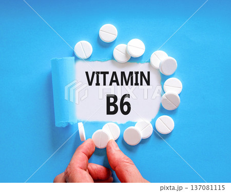 Vitamin B6 symbol. Concept words Vitamin B6 on beautiful white paper. White pills tablets. Doctor's hand. Beautiful blue background. Medical healthy lifestyle Vitamin B6 concept. 137081115