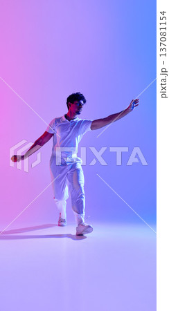 Cricket player in white outfit with extended arm on dark background in delivery stance Cricket player in white outfit with extended arm on dark background in delivery stance 137081154