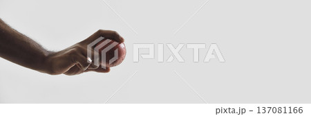 Close up of hand holding red cricket ball on minimal light background. Banner Close up of hand holding red cricket ball on minimal light background. Banner 137081166