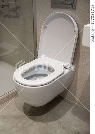 Wall-mounted toilet with open lid bringing a sense of cleanliness and contemporary design to a modern bathroom interior, illustrating hygiene and comfort Wall-mounted toilet with open lid bringing a sense of cleanliness and contemporary design to a modern bathroom interior, illustrating hygiene and comfort 137081718