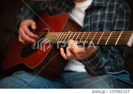 Teenage Boy Playing Acoustic Guitar At Home Strumming Music In Casual Cozy Interior Teenage Boy Playing Acoustic Guitar At Home Strumming Music In Casual Cozy Interior 137082127