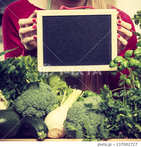 Woman having green vegetables holding board 137082727