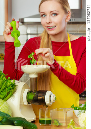 Woman in kitchen making vegetable smoothie juice Woman in kitchen making vegetable smoothie juice 137082734
