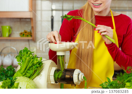 Woman in kitchen making vegetable smoothie juice 137083285