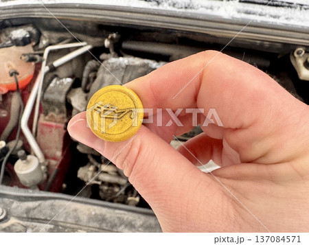 the girl independently checks the oil level in the engine in her personal car and adds a small amount from the bottle. 137084571