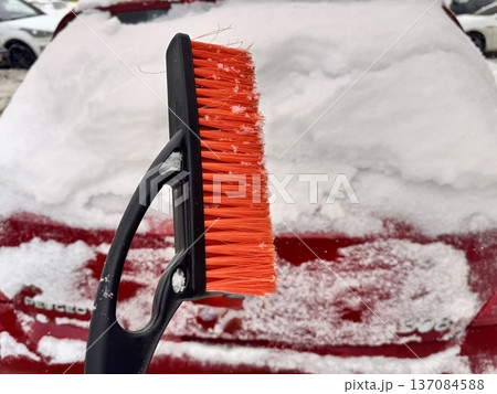 car brush with a scraper in black and orange on a background of snow-white snow on a car in winter car brush with a scraper in black and orange on a background of snow-white snow on a car in winter 137084588
