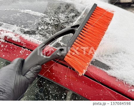 car brush with a scraper in black and orange on a background of snow-white snow on a car in winter car brush with a scraper in black and orange on a background of snow-white snow on a car in winter 137084598