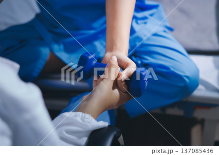 Physical therapist giving stretching exercises with elastic exercise bands and physical therapist hands helping male patient Physical therapy concept Physical therapist giving stretching exercises with elastic exercise bands and physical therapist hands helping male patient Physical therapy concept 137085436