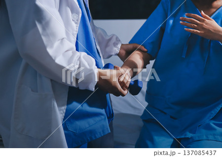 Physical therapist giving stretching exercises with elastic exercise bands and physical therapist hands helping male patient Physical therapy concept Physical therapist giving stretching exercises with elastic exercise bands and physical therapist hands helping male patient Physical therapy concept 137085437