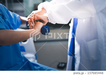 Physical therapist giving stretching exercises with elastic exercise bands and physical therapist hands helping male patient Physical therapy concept Physical therapist giving stretching exercises with elastic exercise bands and physical therapist hands helping male patient Physical therapy concept 137085448
