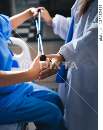 Physical therapist giving stretching exercises with elastic exercise bands and physical therapist hands helping male patient Physical therapy concept Physical therapist giving stretching exercises with elastic exercise bands and physical therapist hands helping male patient Physical therapy concept 137085451