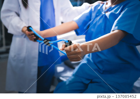 Physical therapist giving stretching exercises with elastic exercise bands and physical therapist hands helping male patient Physical therapy concept 137085452