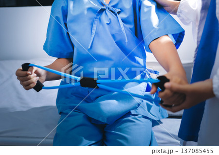 Physical therapist giving stretching exercises with elastic exercise bands and physical therapist hands helping male patient Physical therapy concept Physical therapist giving stretching exercises with elastic exercise bands and physical therapist hands helping male patient Physical therapy concept 137085455