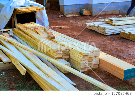 Wooden planks are stacked at construction site as workers prepare for building. Wooden planks are stacked at construction site as workers prepare for building. 137085468