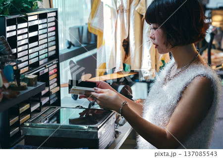 レトロなアイテムが並ぶビンテージショップで買い物をする若い女性 137085543