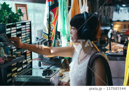 レトロなアイテムが並ぶビンテージショップで買い物をする若い女性 レトロなアイテムが並ぶビンテージショップで買い物をする若い女性 137085544