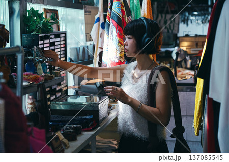 レトロなアイテムが並ぶビンテージショップで買い物をする若い女性 レトロなアイテムが並ぶビンテージショップで買い物をする若い女性 137085545