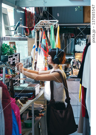 レトロなアイテムが並ぶビンテージショップで買い物をする若い女性 137085547