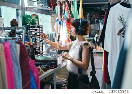 レトロなアイテムが並ぶビンテージショップで買い物をする若い女性 137085548