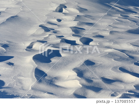 wind-sculpted snowdrifts forming soft abstract patterns and shadows across a frozen landscape 137085557