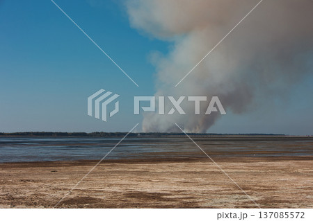 A distant wildfire sends a towering column of smoke into the sky above a small coastal island near Vlora, Albania, captured on August 25, 2025.  137085572