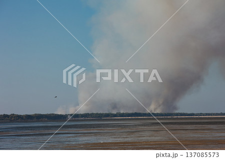 A distant wildfire sends a towering column of smoke into the sky above a small coastal island near Vlora, Albania, captured on August 25, 2025.  137085573