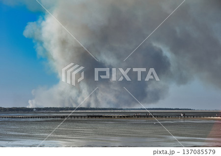 A distant wildfire sends a towering column of smoke into the sky above a small coastal island near Vlora, Albania, captured on August 25, 2025.  137085579