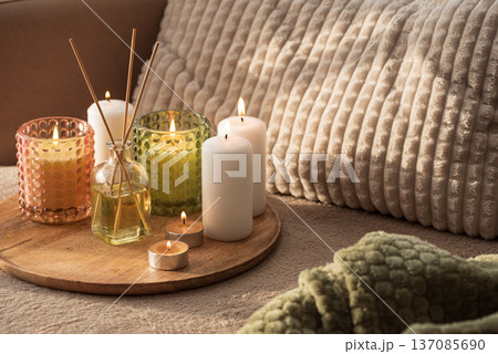Candles and Reed Diffuser on Wooden Tray. Cozy Home Decor lifestyle with Cushions Candles and Reed Diffuser on Wooden Tray. Cozy Home Decor lifestyle with Cushions 137085690